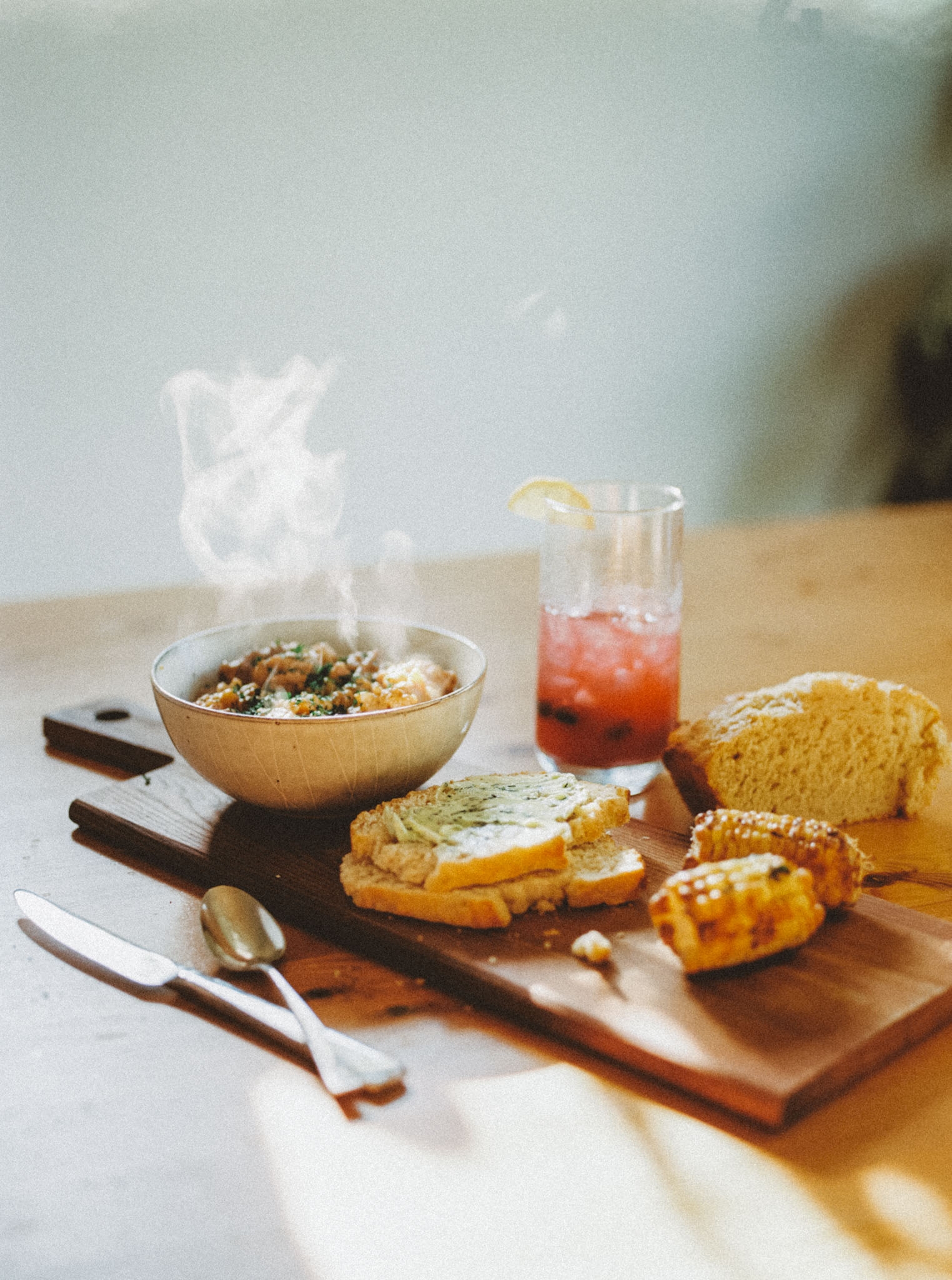 a steaming bowl of food with bread and corn for the lughnasah sabbat