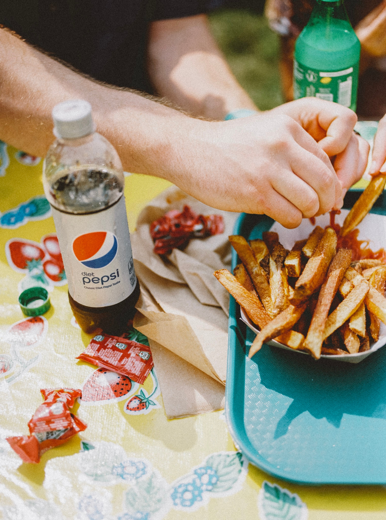 image of a pepsi bottle and french fries on a picnic table